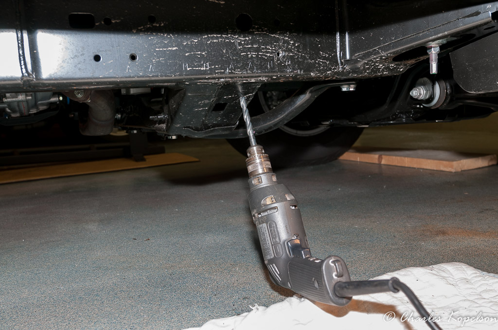 Drilling the hole in the transmission crossmember. The other 2 holes are already there.
