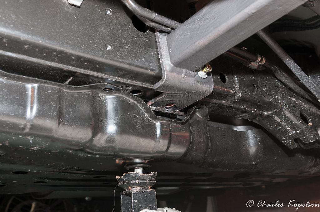 Position the rear mounting bracket behind the hard lines above. Start the gas tank strap bolt making sure it goes through the tank strap and the rear mounting bracket.