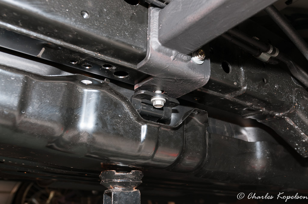 Position the rear mounting bracket behind the hard lines above. Start the gas tank strap bolt making sure it goes through the tank strap and the rear mounting bracket.