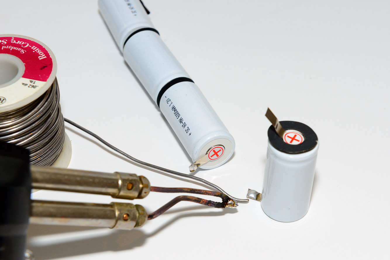 Tin the tabs with solder and place the black insulating washers on the positive side of the batteries.